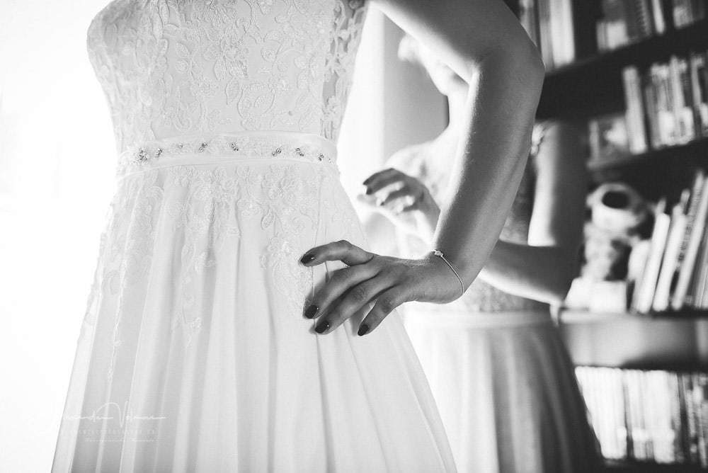 Hochzeitsfotograf fotografiert letzten Schliff am Hochzeitskleid